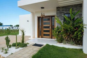 Un bâtiment moderne doté d’une porte en bois, d’un mur en pierre et d’un jardin bien entretenu.