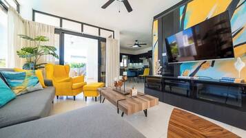 A modern living room with a sofa, yellow chairs, a coffee table, and a TV.