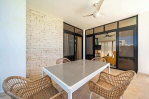 A dining area with a table and wicker chairs, a ceiling fan, and a brick wall. - Private Pool 2BR · Gated Casa Linda · Sosúa (Sosúa)