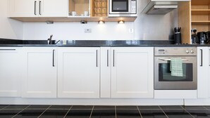 A modern kitchen with white cabinets, a stainless steel microwave, and an oven. - BRIGHTON CENTRAL TRENDY LONGSTAY, WALK TO BEACH (Brighton and Hove)