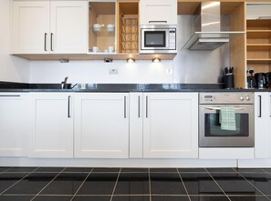 A modern kitchen with white cabinets, a stainless steel microwave, and an oven. - BRIGHTON CENTRAL TRENDY LONGSTAY, WALK TO BEACH (Brighton and Hove)