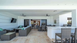 A modern outdoor living area with wicker furniture, a kitchen area, and a dining space.