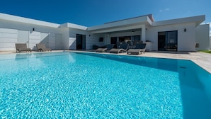 A modern poolside area with lounge chairs and a clear blue pool.