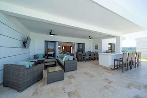 A spacious outdoor living area with wicker furniture, a bar, and a view of the landscape. - 4 king suites • Mega large • Guest house (Sosúa)