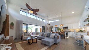 Un vaste espace de vie comprenant un canapé, une table basse et un ventilateur de plafond.