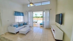 Uma sala de estar com sofá, televisão e vista para uma piscina.