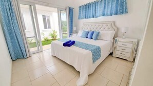 Quarto com cama grande, mesa de cabeceira, janela com cortinas e vista para o exterior.