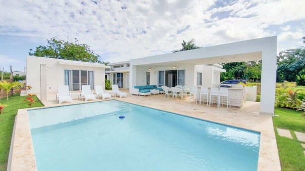 Uma casa moderna com piscina, área de estar ao ar livre e jardim.