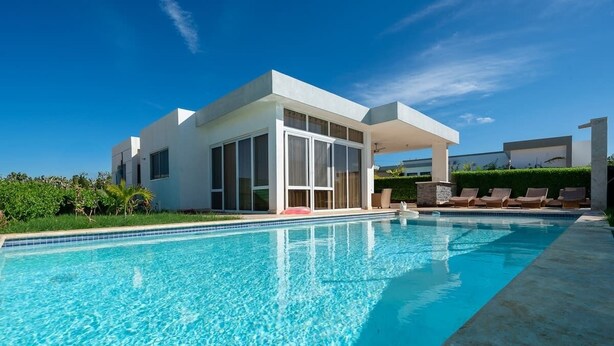 Ein modernes Haus mit Pool, großen Fenstern und einer überdachten Terrasse.