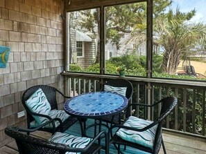 A covered patio with wicker furniture and a mosaic table, overlooking a residential area. - CV4A: Seashell Villa 4A (Ocracoke)