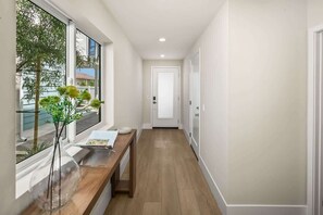 A hallway with a wooden bench, a clear glass vase with plants, and a door at the end. - 3 Minute Walk to Beach 4 Bedroom Home (Carlsbad)