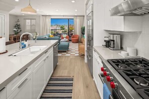 A modern kitchen with a central island, a stove, and a dining area with a view. - 3 Minute Walk to Beach 4 Bedroom Home (Carlsbad)