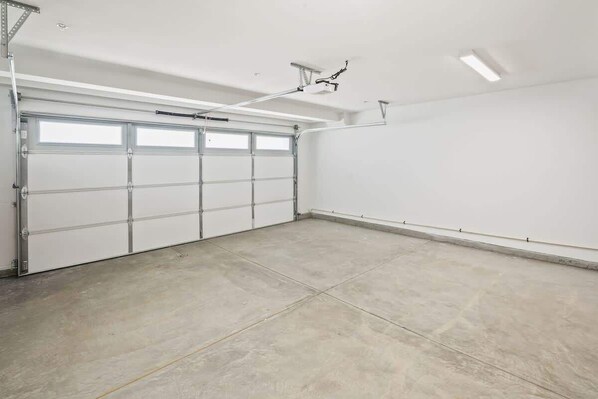 En ren og tom garage med en hvid dør og en lampe monteret i loftet.