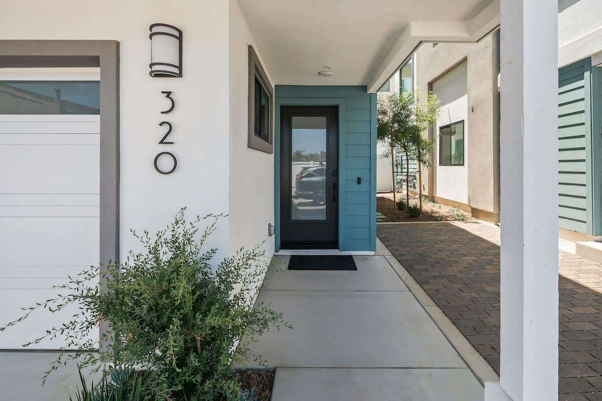 Un bâtiment moderne avec une porte bleue, un garage et le numéro « 320 » peint sur le mur.
