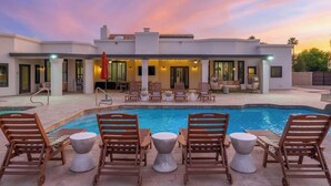 Une maison moderne dotée d’une piscine, de chaises longues et d’un espace patio.