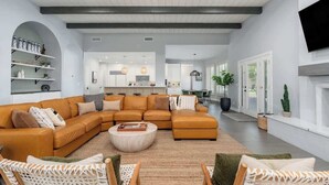 Un salon moderne avec un canapé d’angle, une table basse et des fauteuils en osier.