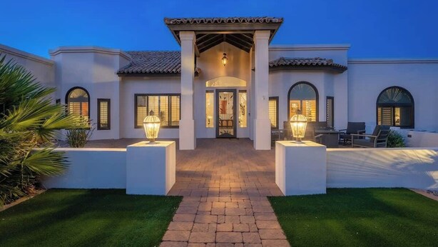 Une maison moderne avec une entrée centrale, un patio couvert et une pelouse bien entretenue.