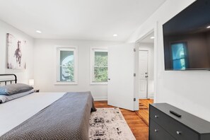 Ein Schlafzimmer mit einem Bett, einem Fernseher und einer Tür zu einem anderen Raum.