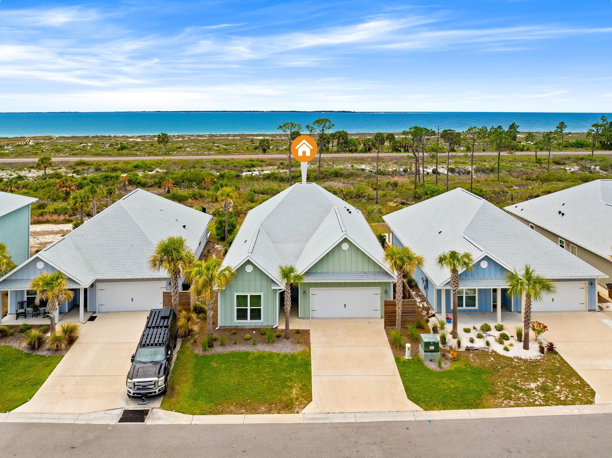 A coastal residential area with multiple houses, a clear view of the ocean, and a prominent house icon indicating a hotel.