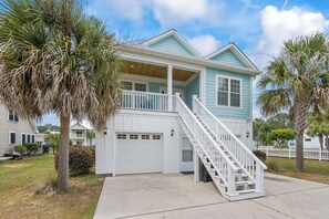 A two-story house with a white garage door, a covered porch, and a staircase leading to the second floor. - 4BR Home Near MarshWalk + Pro Golf Simulator (Murrells Inlet)