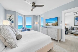 Ein Schlafzimmer mit Bett, Deckenventilator, Fernseher, Kommode und Meerblick.