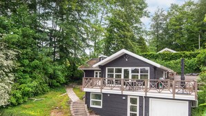 Une maison à deux étages avec un balcon, un garage et un jardin.