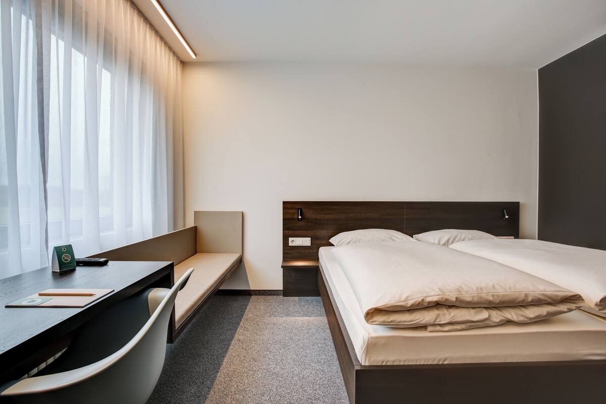 A hotel room with a bed, a desk, and a chair.