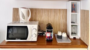 Un coin cuisine équipé d’un four à micro-ondes, d’une bouilloire, d’une étagère avec des paniers et d’un grille-pain.