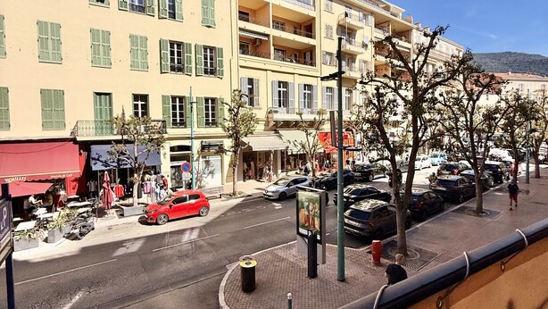 Une vue de rue avec des immeubles, une voiture rouge et un passage pour piétons.