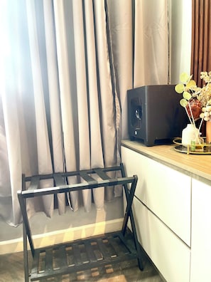 Ein Zimmer mit Schreibtisch, Lautsprecher in Schwarz und einer Vase mit Blumen.