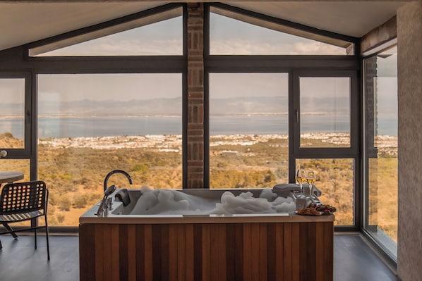 Une salle de bain moderne avec une grande baignoire, un lavabo et une chaise, donnant sur un paysage pittoresque.