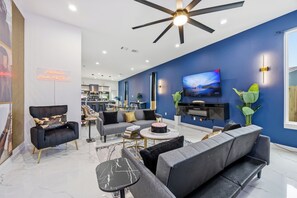 Un salon moderne doté d'un ventilateur de plafond, d'un téléviseur à écran plat et d'un néon.