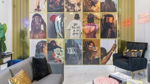 Un interior moderno con un sofá gris, un sillón negro y una pared decorada con imágenes enmarcadas.