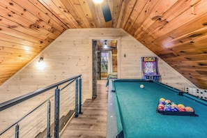 Un intérieur en bois avec une table de billard et une table de jeux.