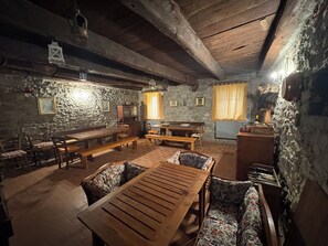 A rustic dining area with wooden benches and tables, stone walls, and a chandelier. - Charming ancent Stone Houes  located near Lucca (Colognora)