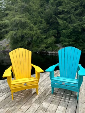 Two Adirondack chairs on a wooden dock with a forested lake in the background. - Enchanting Bay Cottage (Parry Sound)