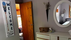 Un dormitorio con una cama, un aparador, un espejo y un cartel de bienvenida.