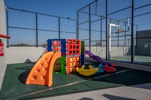 Une aire de jeux avec un toboggan, des structures d’escalade et des balançoires.