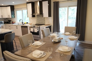 Een moderne keuken met een eethoek, met een groot schiereiland, inbouwapparatuur en uitzicht op de omgeving.