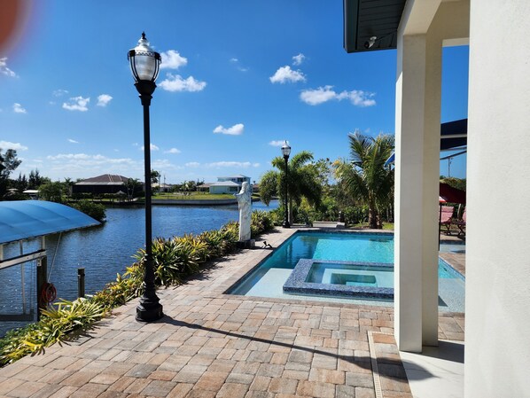 A swimming pool with a view of a body of water, a statue, and a lamp post.
