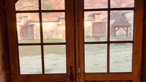 A wooden double door with a view of a backyard.