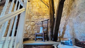 A staircase with a stone wall, a wooden chair, and a white railing.