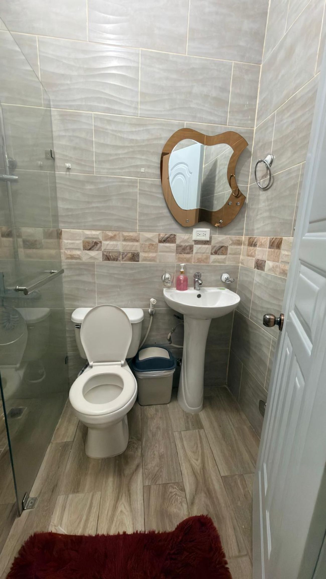 Een badkamer met toilet, wastafel en spiegel.