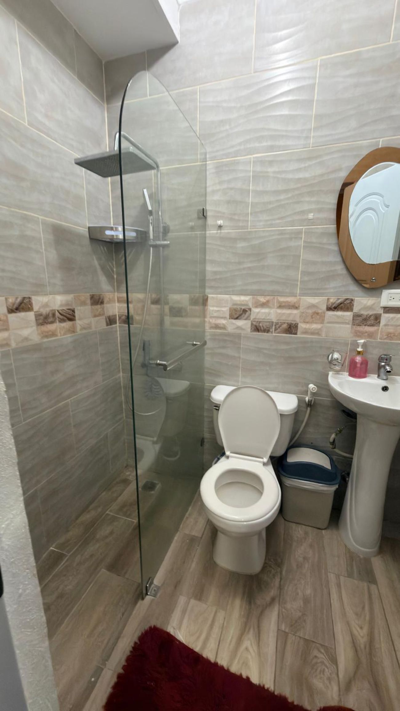 Ein Badezimmer mit Duschkabine, Toilette, Waschbecken und Spiegel.