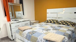 A bedroom with a bed, a dresser, a mirror, and an air conditioning unit.