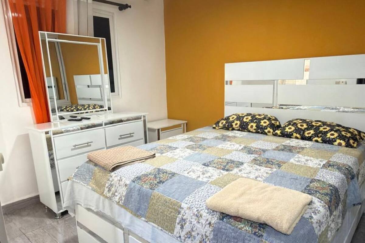 A bedroom with a bed, a dresser, a mirror, and an air conditioning unit.