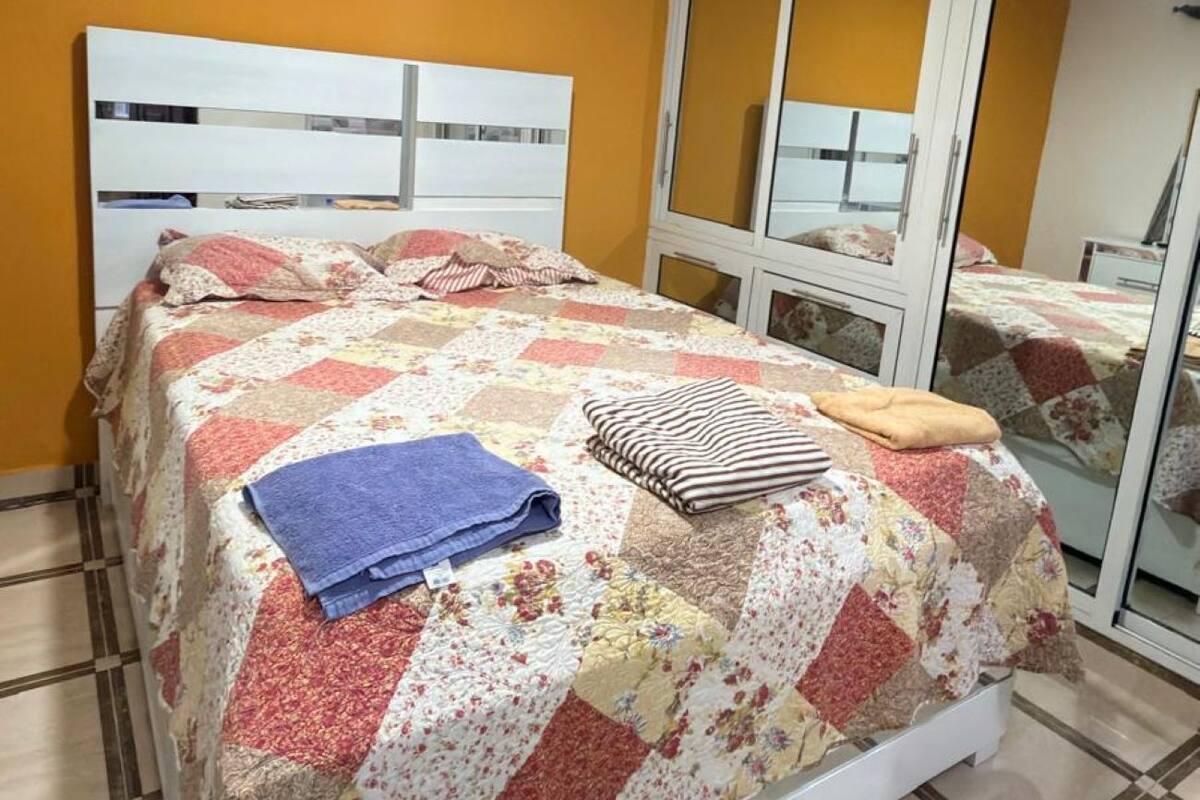 A bedroom with a bed, a ceiling fan, a window, and a mirror.