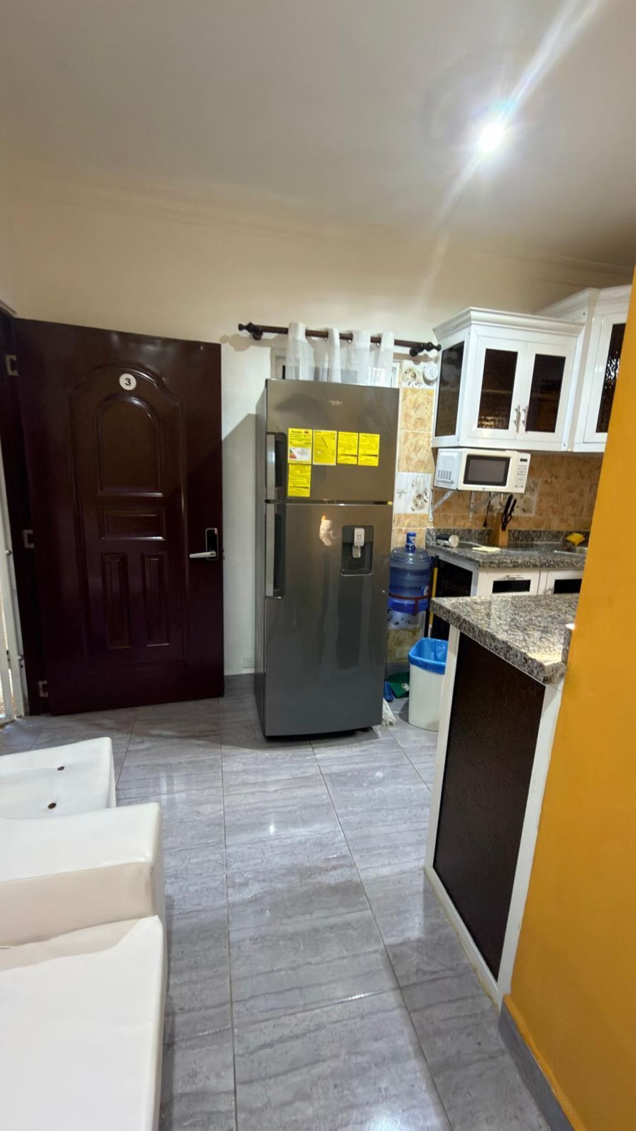 A compact kitchen with a refrigerator, a microwave, and a water dispenser.