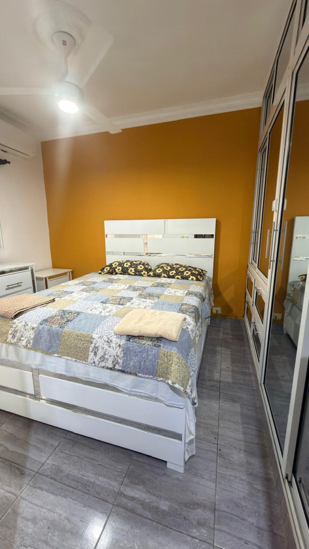 A bedroom with a bed, a wardrobe, a ceiling fan, and a window.