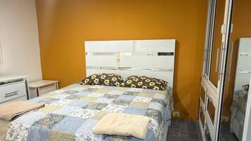 Een slaapkamer met een bed, een kledingkast, een plafondventilator en een raam.